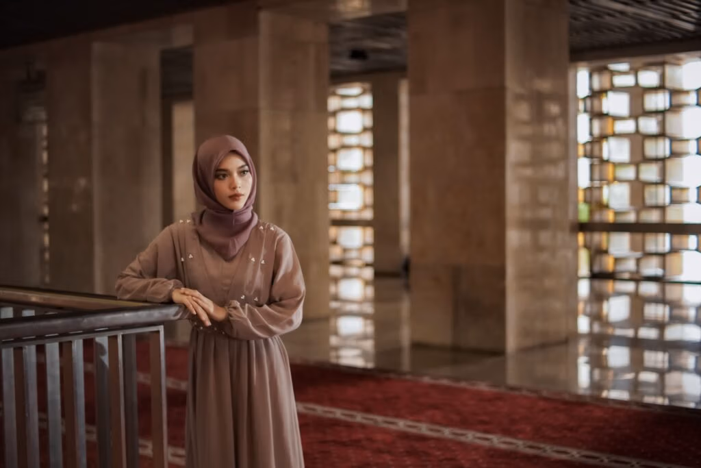 A serene portrait of a woman in traditional dress standing inside Istiqlal Mosque, Jakarta.