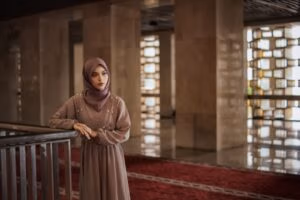 A serene portrait of a woman in traditional dress standing inside Istiqlal Mosque, Jakarta.