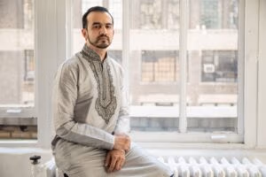A man in traditional clothing sits by a window, capturing a blend of cultural and modern design.